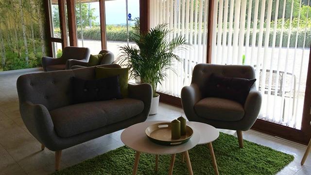 Moderne stue med grå sofaer, grønne puder, et rundt bord og en plante på et grønt tæppe.