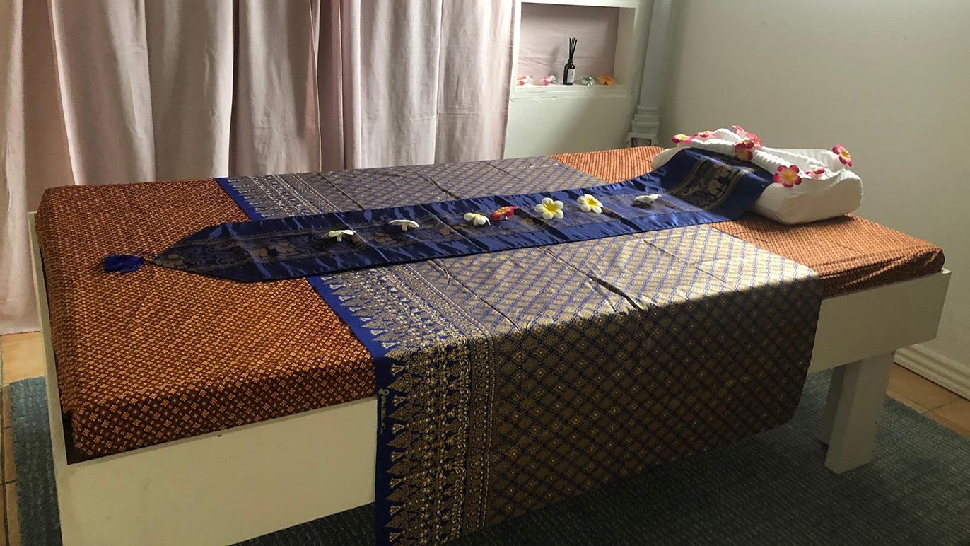 En massagebriks dækket med farverige tekstiler og dekorationer i et lyst rum.