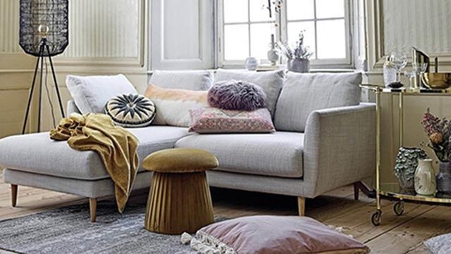 Moderne stue med en lys sofa, farverige puder, et lille bord og dekorative genstande i et stilfuldt miljø.