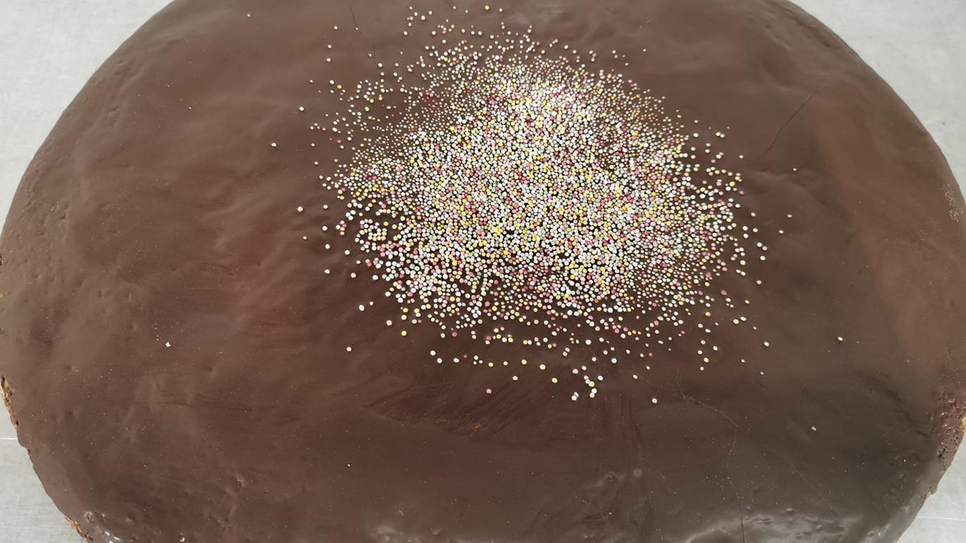 En chokoladefondant med glitrende pynt på toppen, placeret på bagepapir.