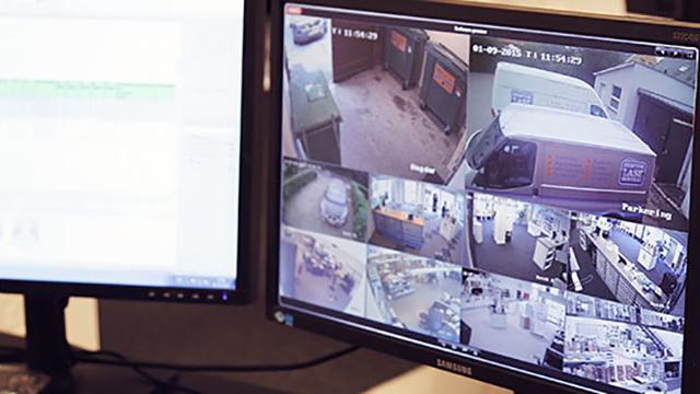 Overvågningskameraer viser forskellige områder af en butik og parkeringsplads på computerskærme.