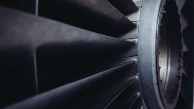 Nærbillede af en jetmotor med detaljerede turbineblade og metaloverflader.