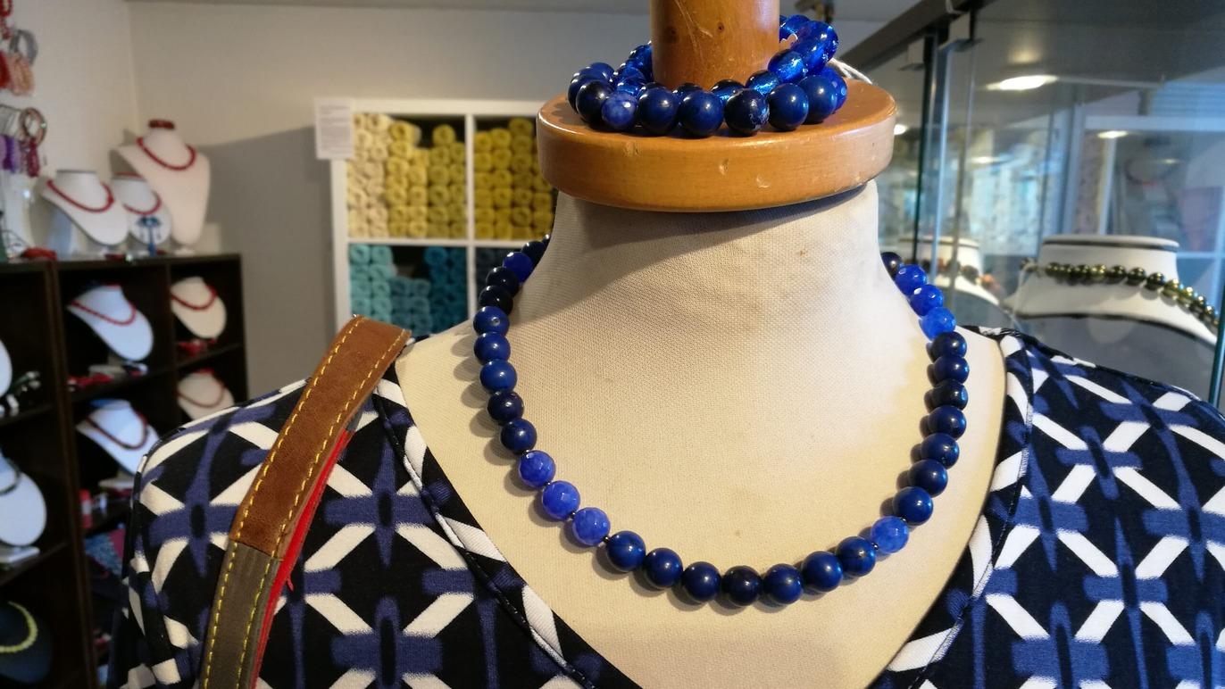 Blå lapis lazuli halskæde og armbånd præsenteret på en mannequin i en smykkebutik.