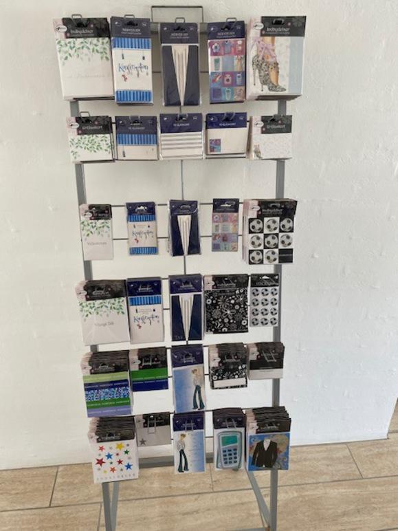 En stålreol med forskellige klistermærker og dekorationer til scrapbooking og håndværk.
