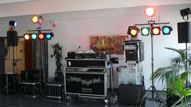 Et DJ-setup med lys og højtalere i et festlokale, klar til at underholde gæsterne.
