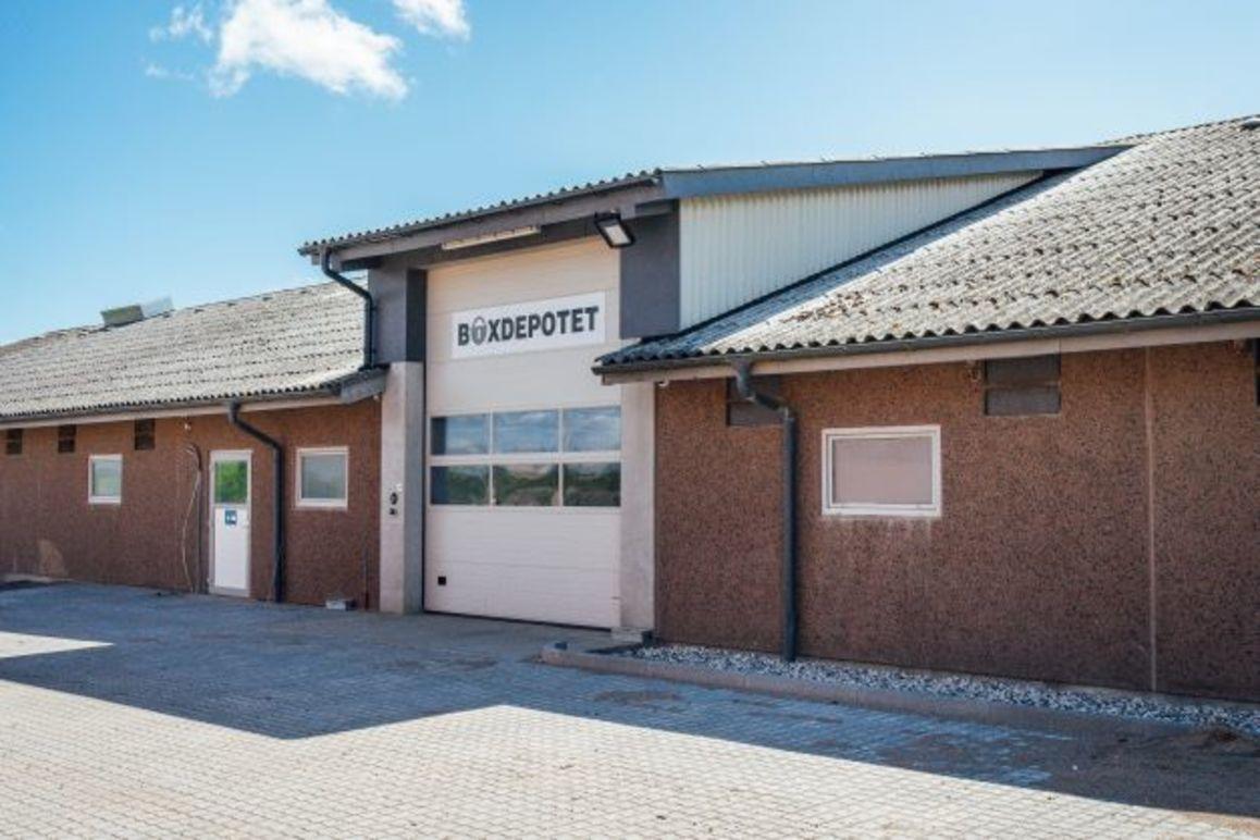 En bygning med en stor garageport og skiltet "Biodukket" på facaden under en blå himmel.
