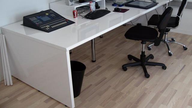 Moderne kontor med et hvidt skrivebord, to kontorstole og en affaldsspand på gulvet.