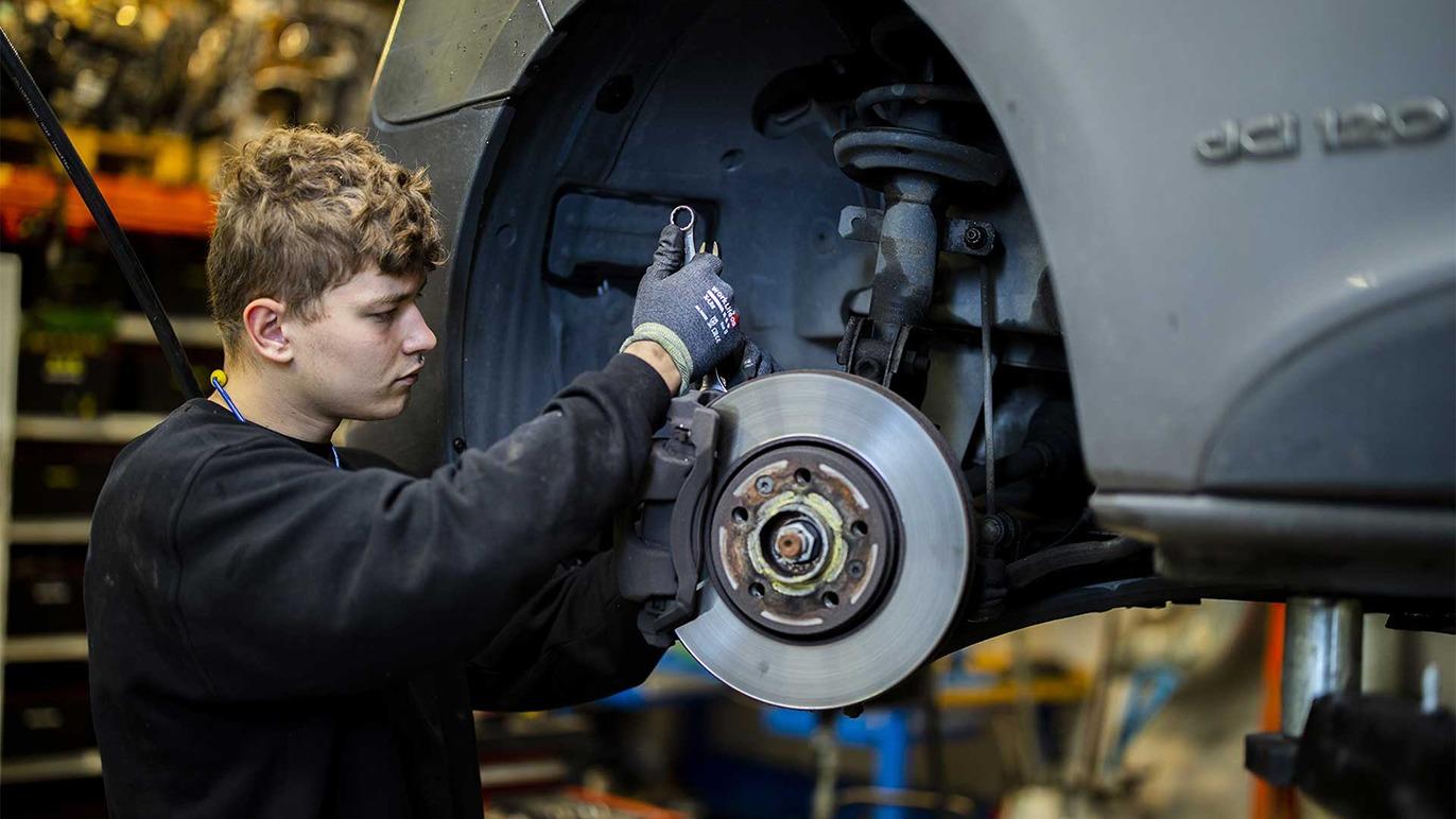 En mekaniker arbejder på bremserne på en bil i et værksted.
