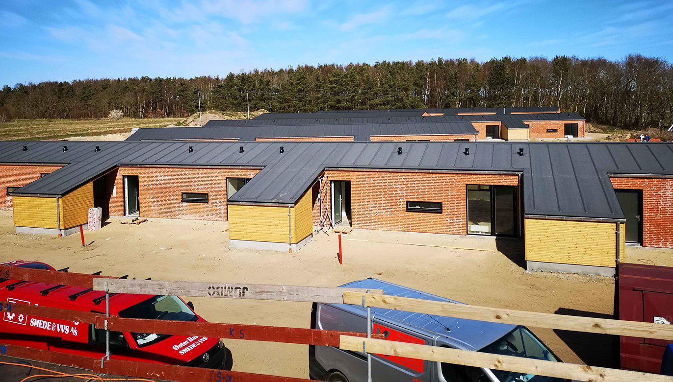 Nyt boligområde med moderne huse i træ og metaltag, beliggende i naturskønne omgivelser.