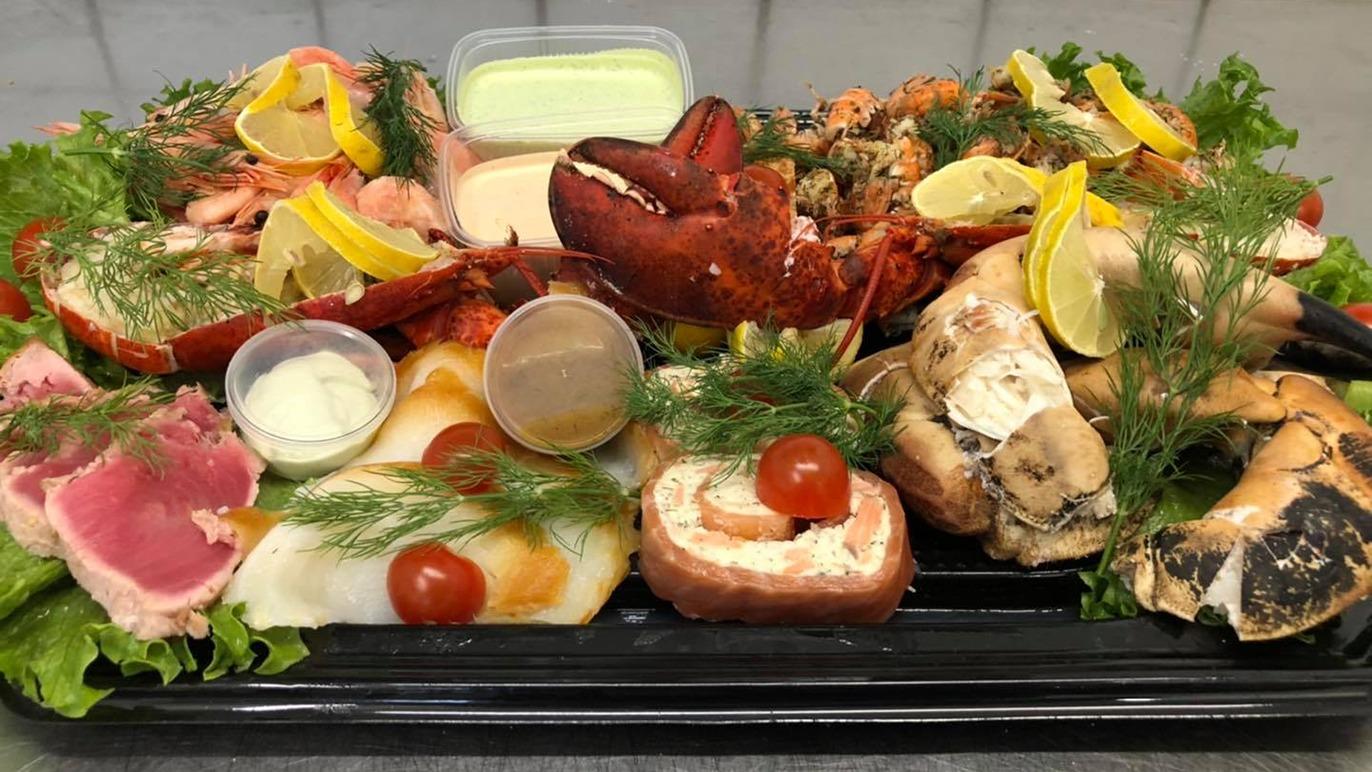 En lækker skaldyrsplatte med rejer, hummer, fisk, salat, citron og forskellige saucer.