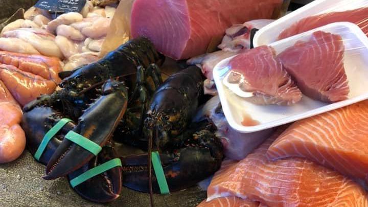 Frisk fisk og skaldyr på markedet, herunder hummer, laks og tun i forskellige former.