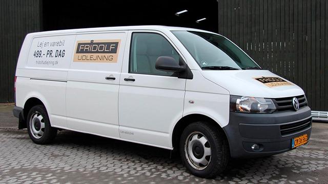 Hvid varevogn med reklame for Rigolf Udlejning parkeret på brosten.
