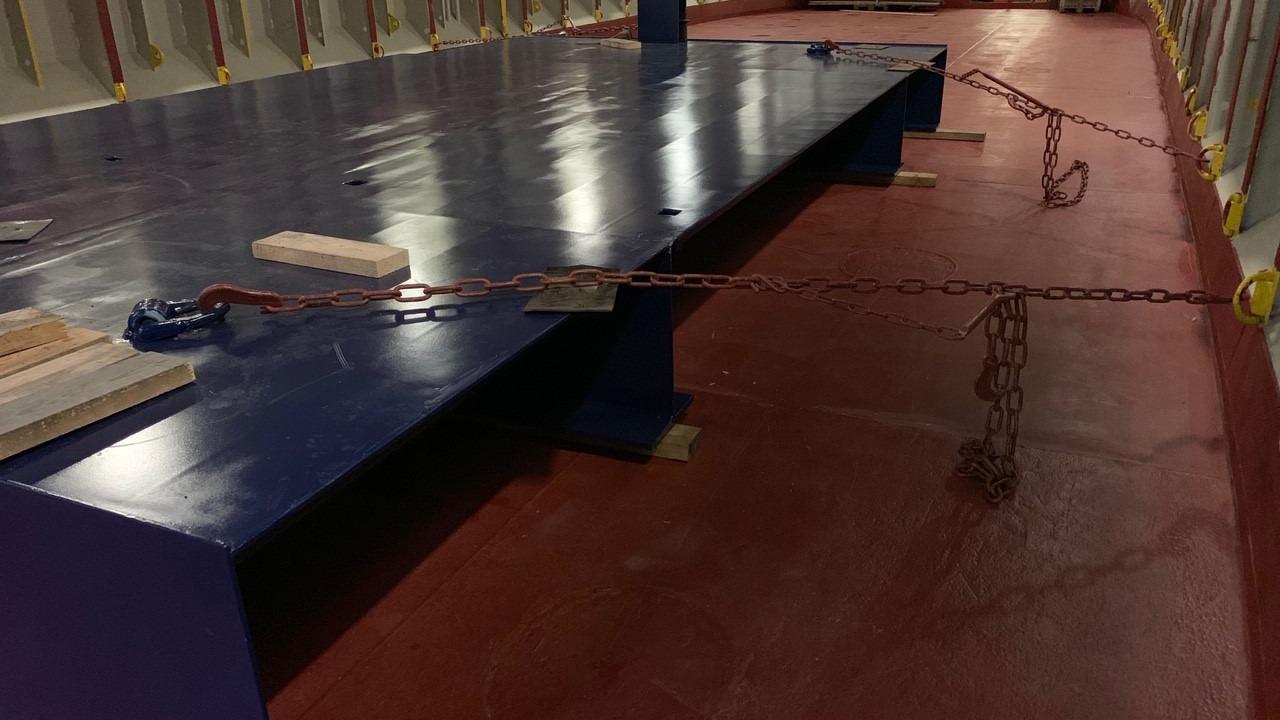 Billede af en stor, blå platform med kæder og træplanker på en rød gulvbelægning i et indendørs rum.