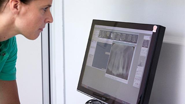 En kvinde ser koncentreret på en computerskærm med røntgenbilleder.