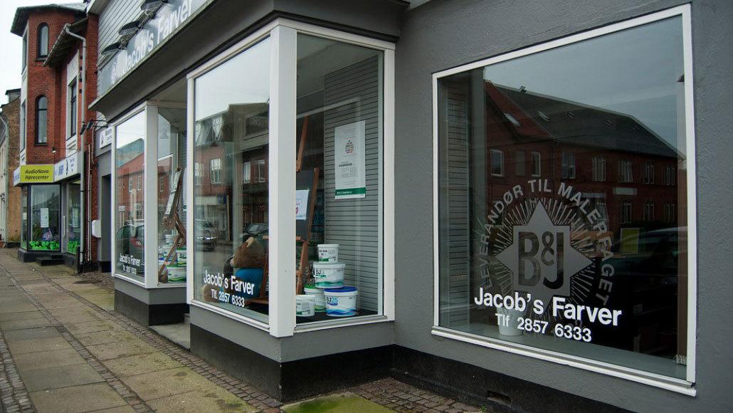 Facade af Jacob's Farver med vinduer, der viser malerprodukter og farver i en bygade.