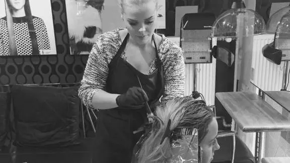 Frisør arbejder med hårfarvning på en kunde i en moderne salon med stilfuld indretning.