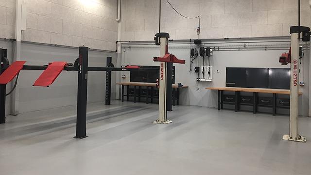 Et moderne værksted med løftebænke, arbejdsborde og udstyr til bilreparation.