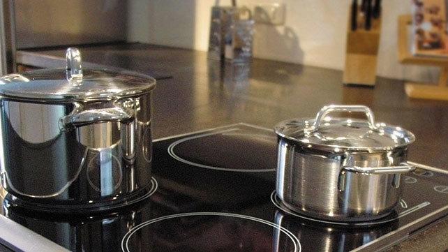 To store og blanke gryder på en induktionskogeplade i et moderne køkken.