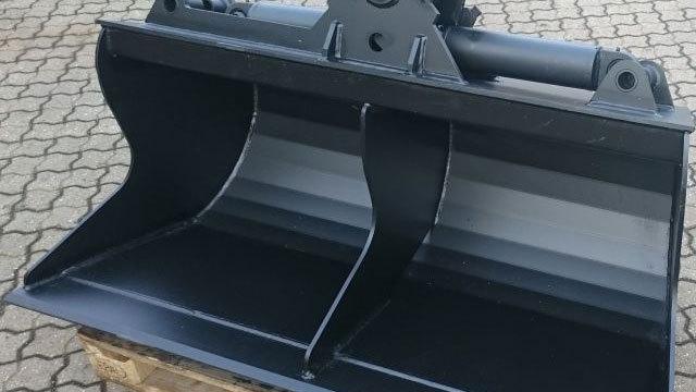 En sort skovl med to skovle, designet til gravemaskiner, står på en palle på en brostenbelagt overflade.