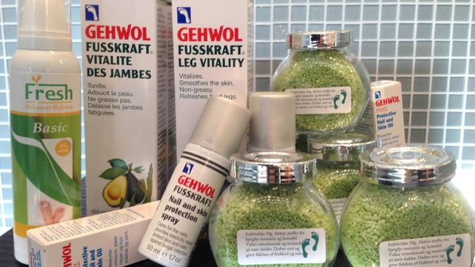 Billede af forskellige Gehwol fodplejeprodukter, herunder cremer og fodbadssalt i grønne glasbeholdere.