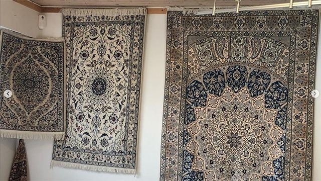 Tre smukke tæpper hængende på væggen, med detaljerede mønstre i blå og beige nuancer.