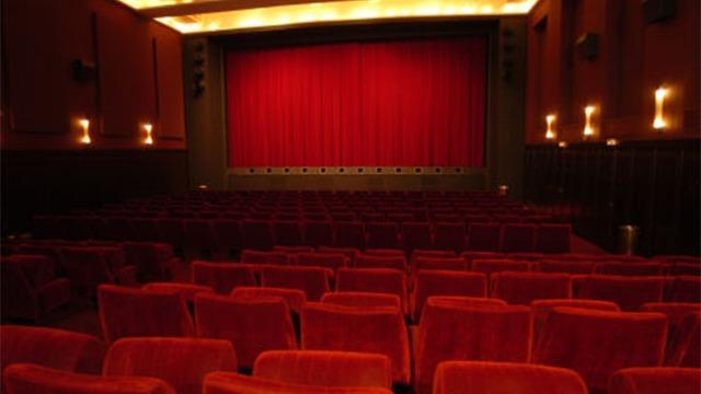 En tom biograf med røde sæder og en rød scene med forhæng klar til en filmvisning.