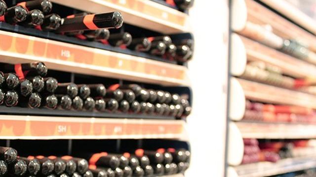 Hylder med forskellige læbestifter i en skønhedsbutik, organiseret efter farver og nuancer.