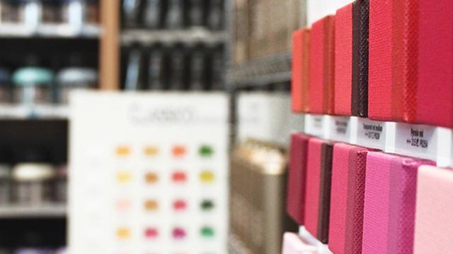 Farveprøver af maling i en butik med forskellige nuancer af rød og pink i fokus.
