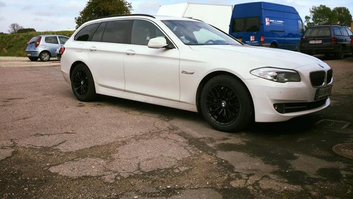 En hvid BMW stationcar med sorte fælge parkeret på en grusvej.