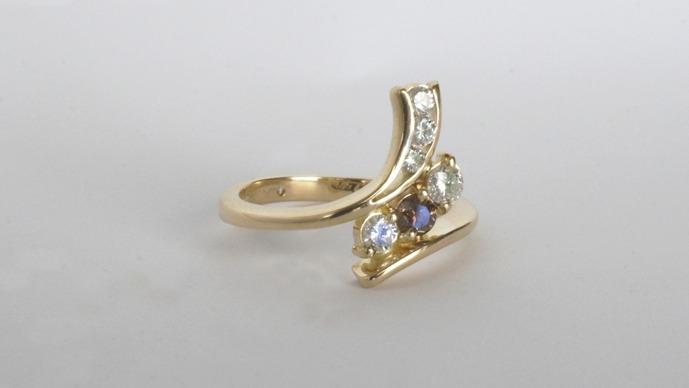 En elegant guld ring med flere farverige ædelsten og en unik design.