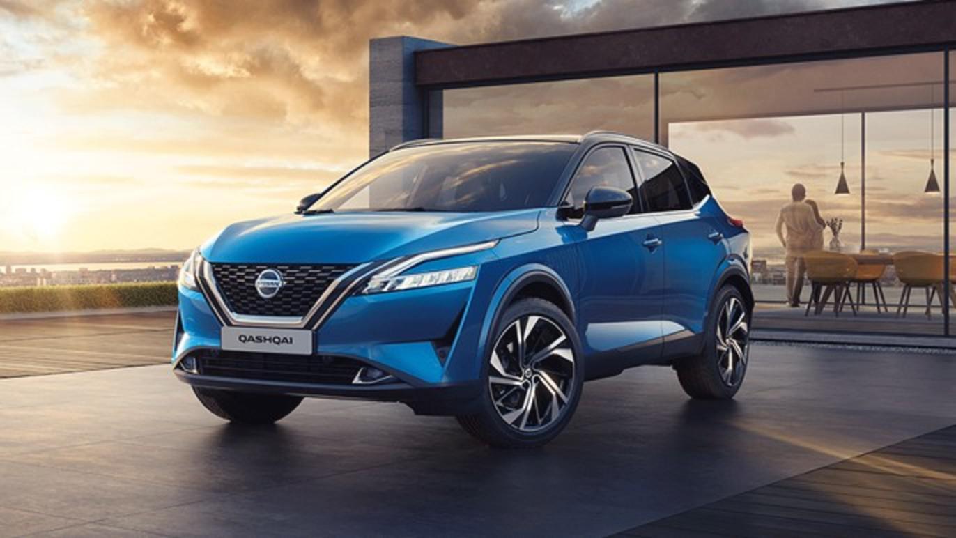 En blå SUV fra Nissan står foran en moderne bygning med store vinduer og en solnedgang i baggrunden.