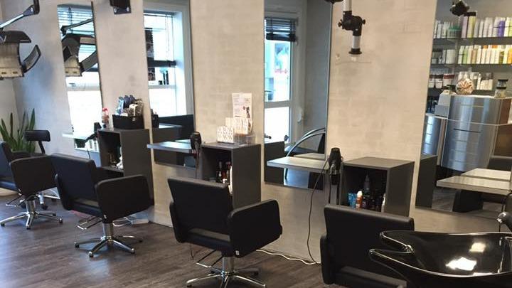 En moderne frisørsalon med spejle, stole og hårprodukter på hylderne.