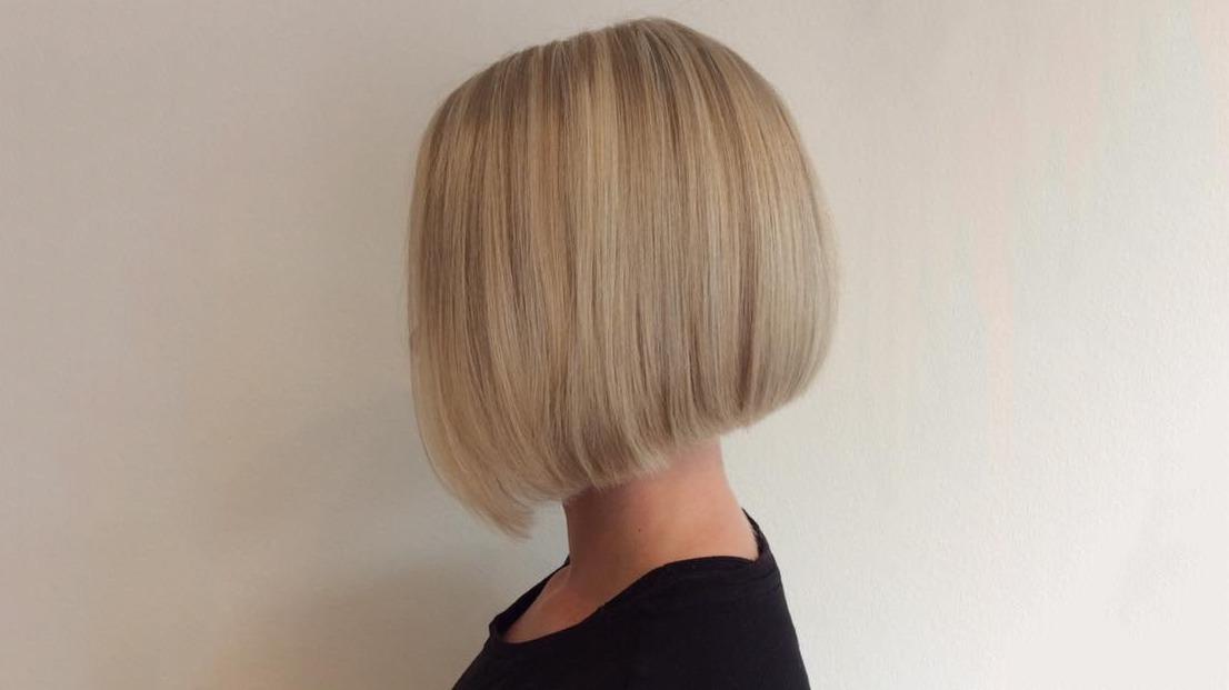 En kvinde med en kort, lige bob-frisure i lys blond hår set fra siden.