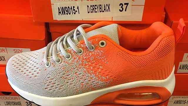 En orange og grå sportsko med luftstødabsorbering, placeret på en kasse med størrelse 37.