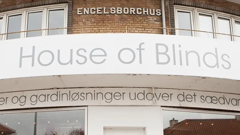Facade af House of Blinds med skilt og tekst om gardiner og gardinløsninger.
