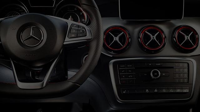 Interiør af en Mercedes bil med læderrat og moderne kontrolpanel med runde luftudblæsere.