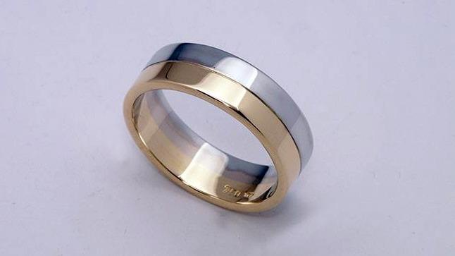 Et moderne vielsesring i sølv og guld med en glat overflade og en elegant design.
