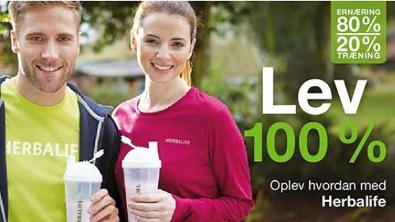 To personer i sportstøj holder shakerflasker og smiler, med teksten "Lev 100%" og "Herbalife" i baggrunden.