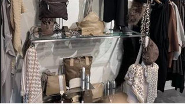 En moderne udstilling af tasker og accessories på en glasdisk i en tøjbutik.