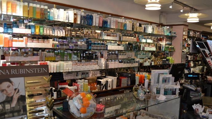 En kosmetikbutik med hylder fyldt med skønhedsprodukter og parfumer, samt en disk med kasseapparat.