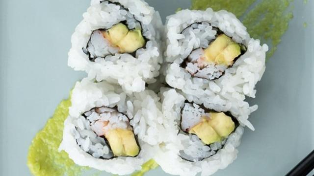 Fire stykker sushi med ris, tang, rejer og avocado på en tallerken med wasabi.