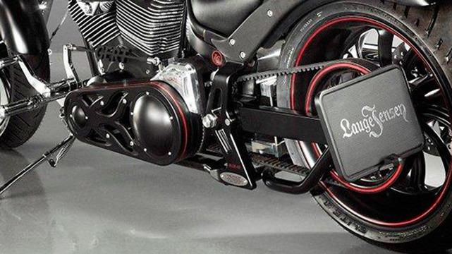Detalje af en motorcykel med sort motor, rød kant og en kraftig kædetræk.