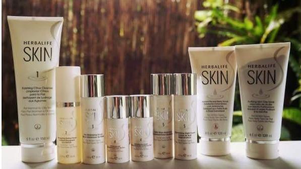 Billede af en række Herbalife Skin hudplejeprodukter på en hvid overflade med grønne planter i baggrunden.