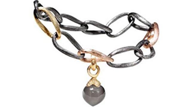 Et smukt armbånd med kæder i sort og guld samt en grå hængende perle.