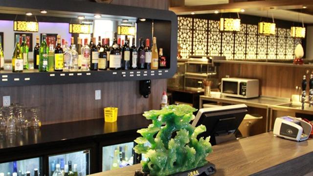En bar med et udvalg af spiritusflasker, en grøn dekoration og moderne indretning i en restaurant.