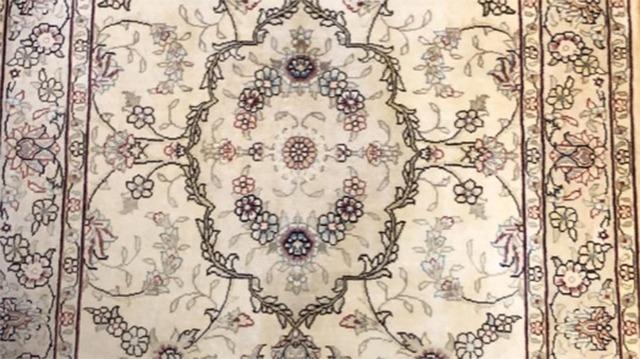 Et smukt orientalsk tæppe med blomsterdesign og detaljerede mønstre i bløde farver.