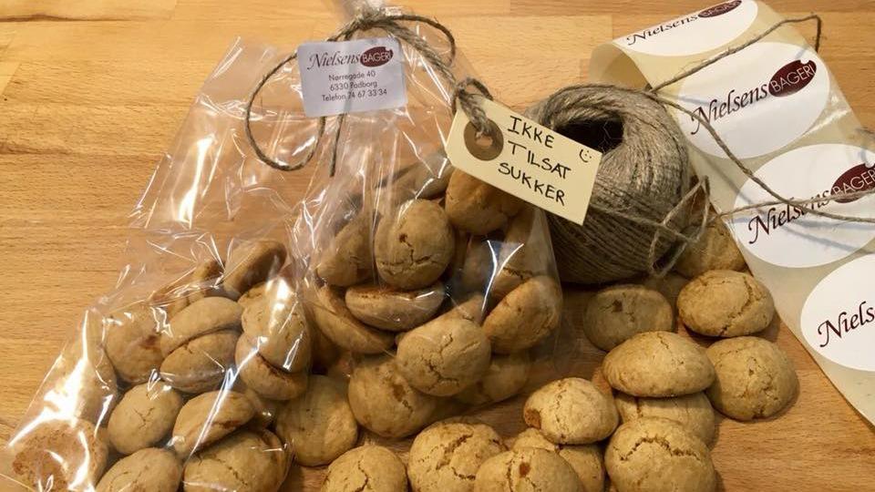 Hjemmelavede småkager i en plastikpose med et mærke og snor, placeret på et træbord.