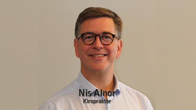 Portræt af Nis Alnor, en kiropraktor, der smiler mod kameraet med briller og en lys skjorte.