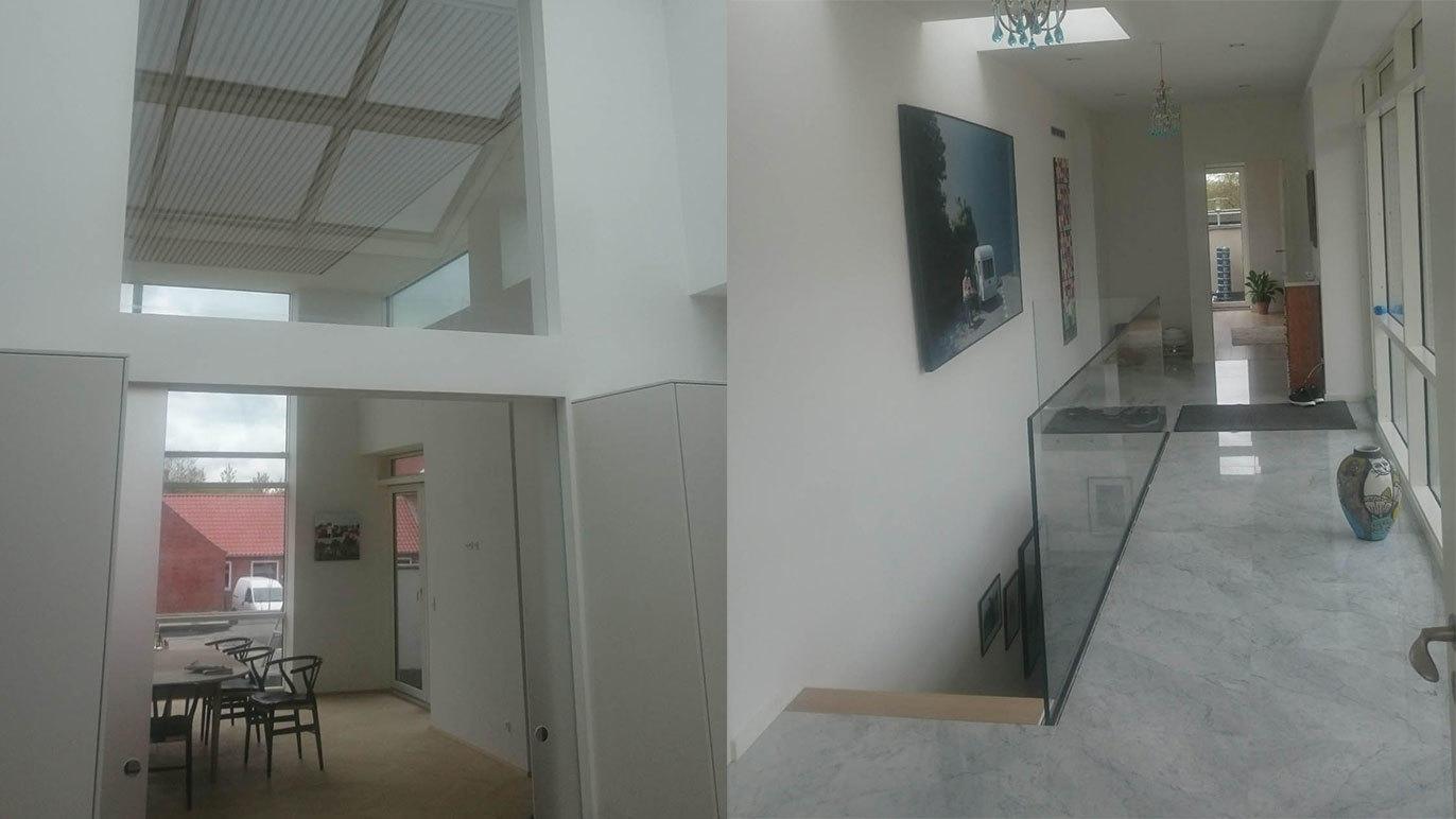 Moderne indretning af en lys stue med åbent køkken og elegant gang med kunstværker på væggene.