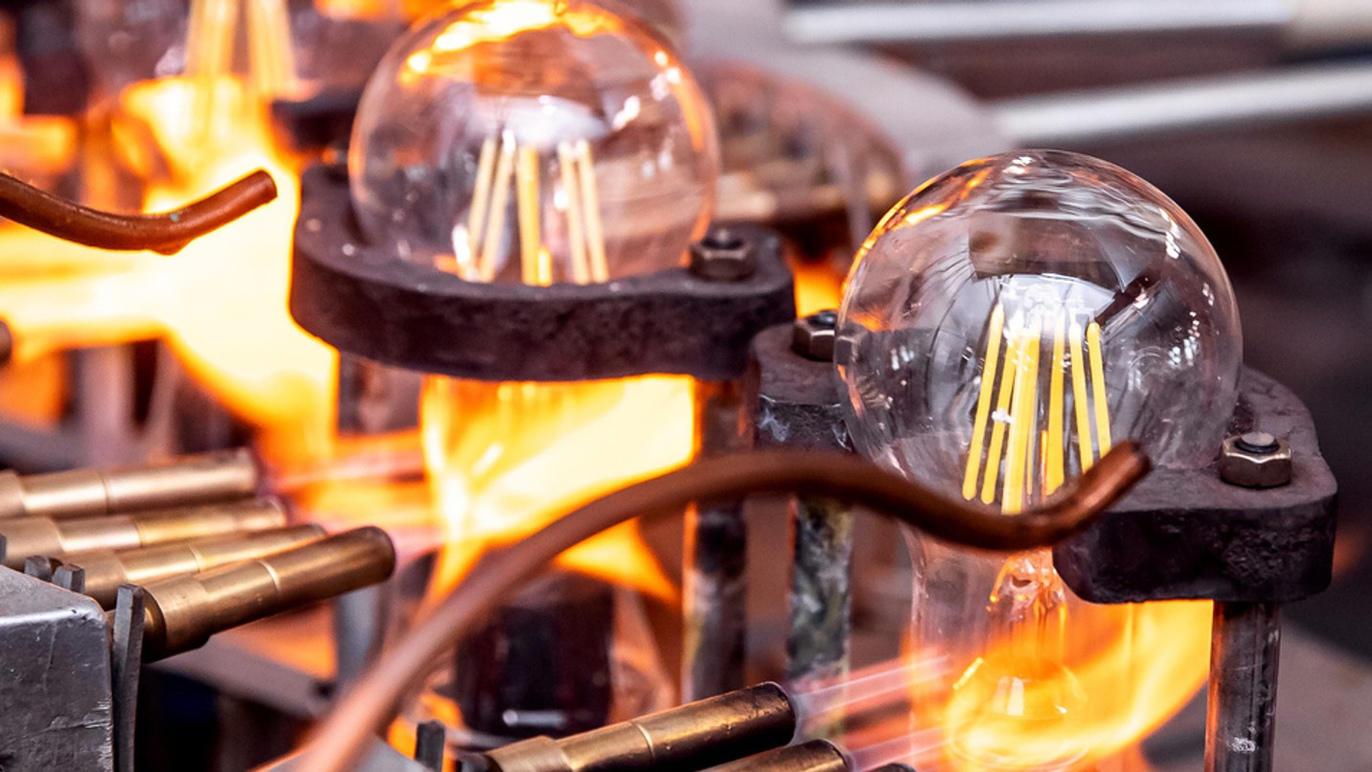 Glødepærer i produktion med flammer og metaldele i en fabrik.